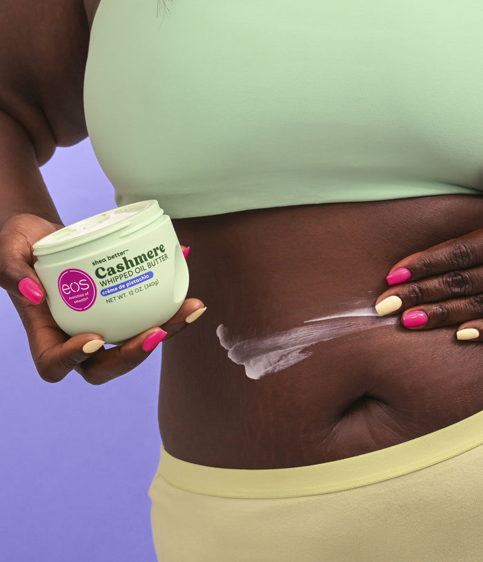 Person applying EOS body butter to their skin with a purple background