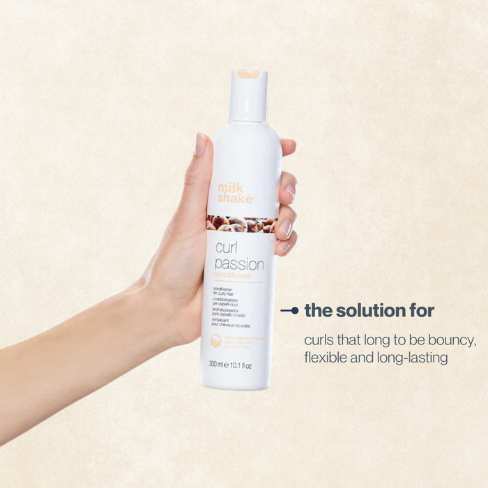 Hand holding a bottle of milk_shake curl product against a beige background