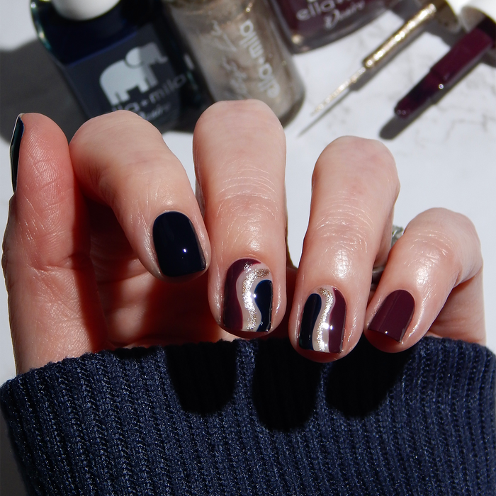 Gladiator Bronze liner accents on a dark navy and burgundy manicure with the bottles