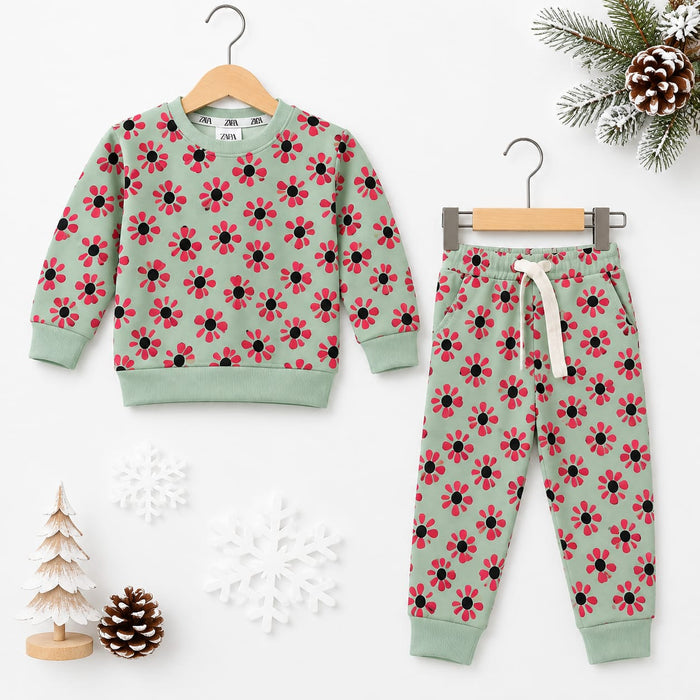A children's two-piece sweatshirt and jogger pants set in sage green, featuring a red and black floral pattern. The sweatshirt is shown on a wooden hanger on the left, and the matching pants are on a metal hanger on the right.