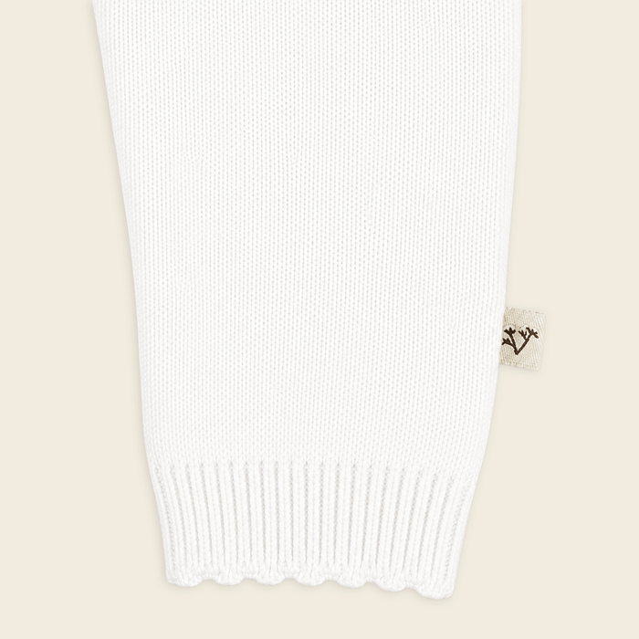 close up of sleeve from milan dove white delicate pointelle knit baby jumpsuit made with organic cotton