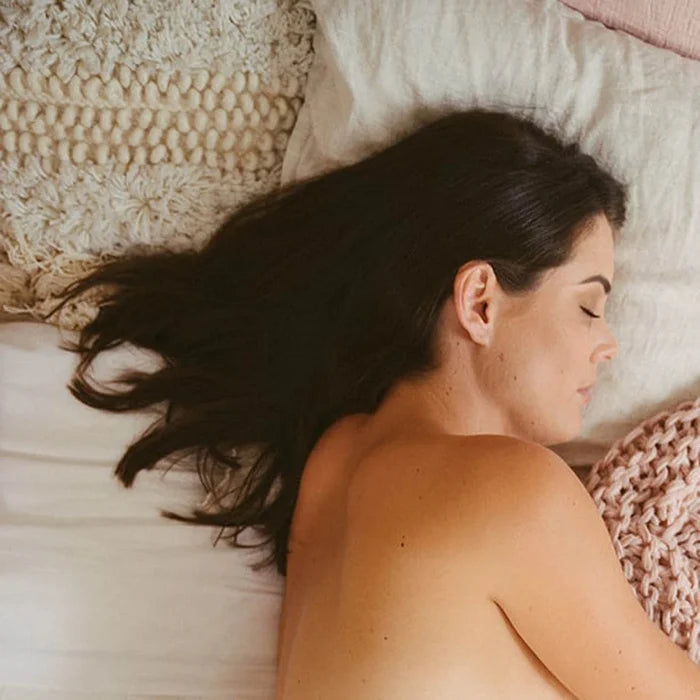 Woman lying on a bed with soft bedding and pillows