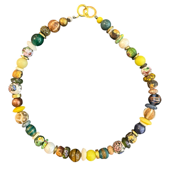 A multicolor beaded necklace with a gold clasp, featuring a mix of round and textured glass beads in yellow, green, blue, brown, and white, displayed on a solid white background.
