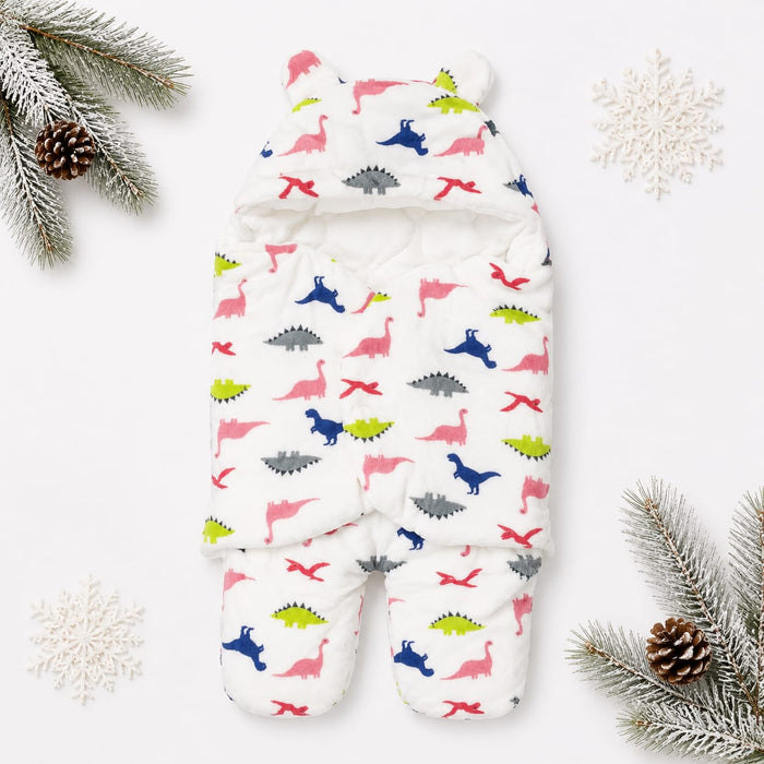A white hooded baby sleeper with a colorful dinosaur print, styled in a flat lay with pine branches, snowflakes, and pinecones on a white background.