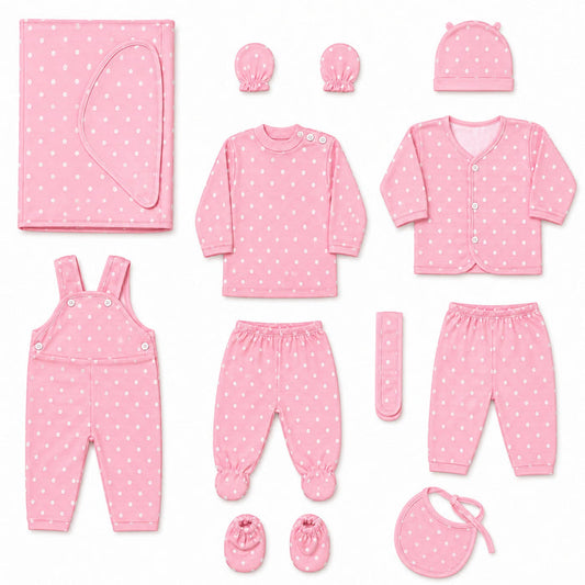A baby clothing set arranged on a white background, including a pink long-sleeve top, matching pants, cardigan, overalls, booties, bib, hat, swaddle, and a small remote control, all in a light pink fabric with small white polka dots.