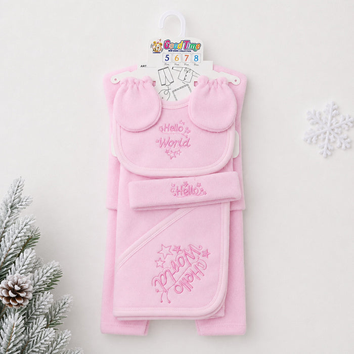 A pink baby gift set hanging on a white hanger against a light background, featuring a bib with 'Hello World' embroidery, a matching hat, and a hooded towel with 'My First Party' embroidery. Decorative pine branches and a snowflake are visible at the edge