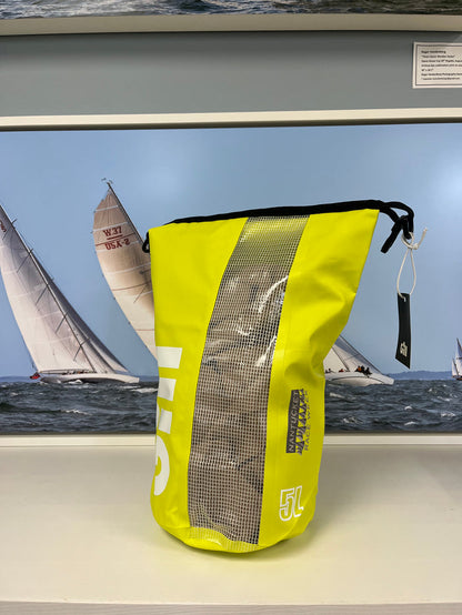 Yellow dry bag with mesh side on a shelf in front of a sailboat picture