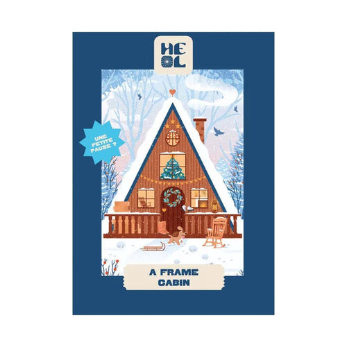 Illustration of an A-frame cabin in snow with a wreath, snowman, rocking chair, and trees. Text: "A-Frame Cabin." Heol Editions' A-Frame Cabin | 99 Piece Jigsaw Puzzle is perfect for Christmas and made in France.
