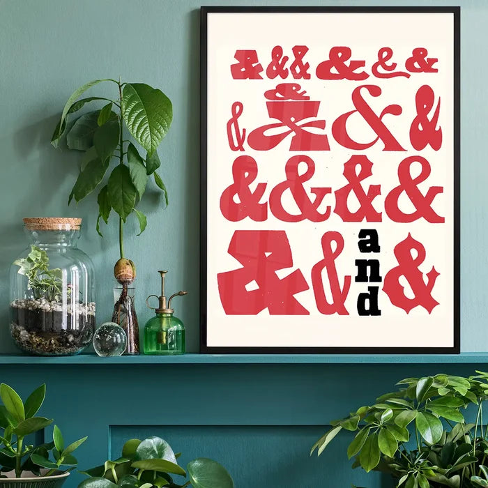 Red and black ampersands in various fonts on a cream background, framed in black, on a teal shelf.