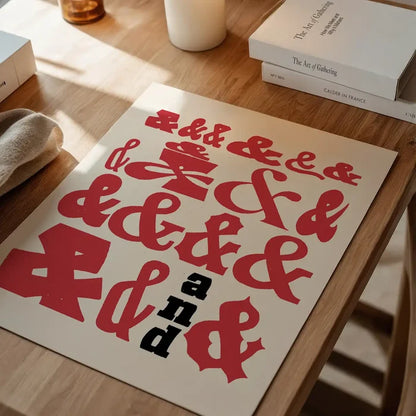 Red and black ampersands typography print on thick, archival art paper, displayed on a wooden table.