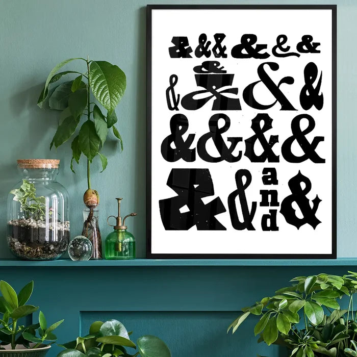 Black and white typographic print featuring various ampersand designs in a black frame on a teal shelf.