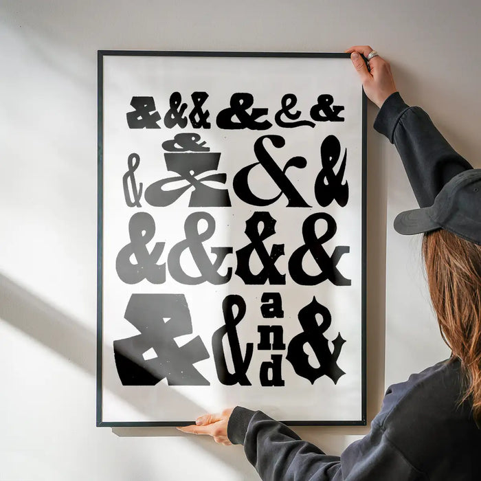 Black and white Ampersands Typography Print on archival paper, held by hands, in a black frame.