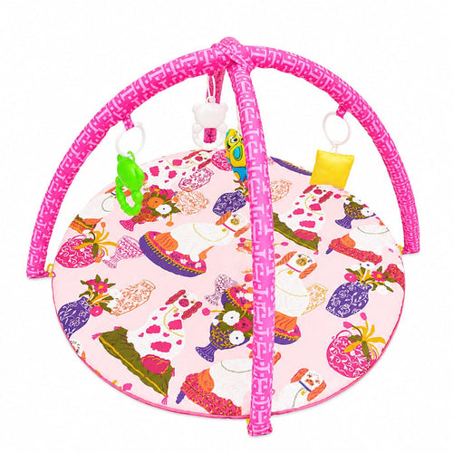 A baby activity gym with a pink frame and a round play mat featuring a colorful fashion-themed print, complete with hanging toys.