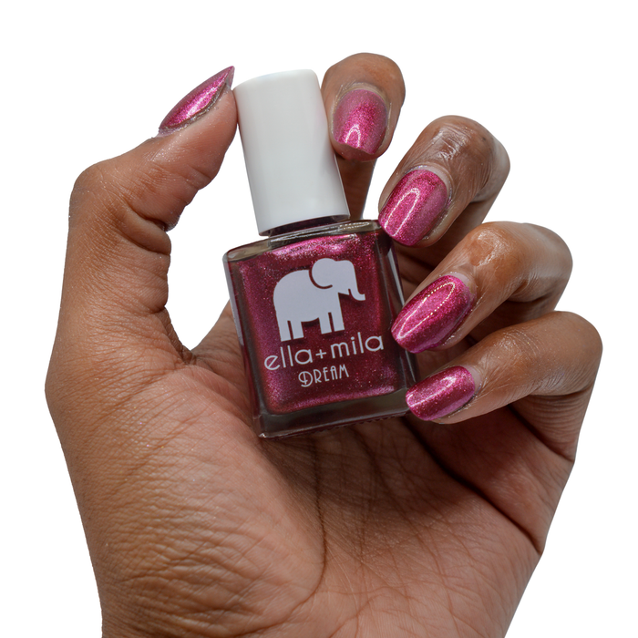 Bang Bang purple-pink metallic nail polish on a deep skin tone, hand holding the bottle