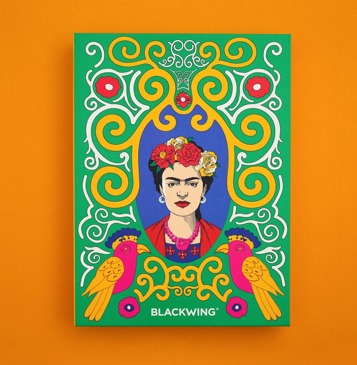 A colorful Frida Kahlo stationery box set featuring colors of yellow and white swirls, with two and orange pink birds at the bottom and the text BLACKWING, shown against a solid orange background.