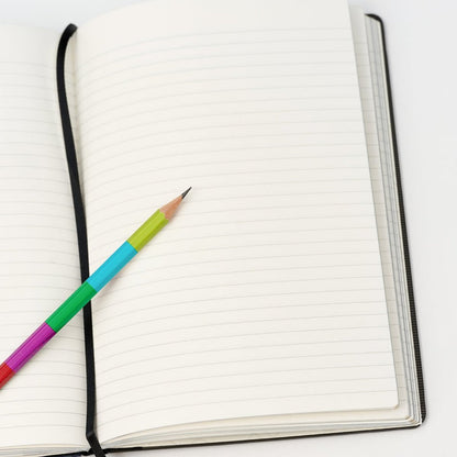 lined notebook laying open with a sharpened colorblock pencil on top.