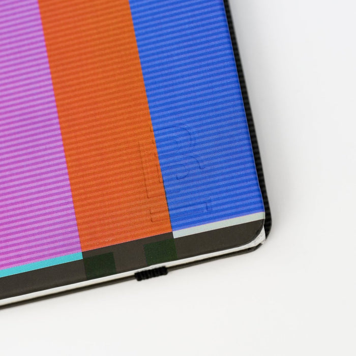 close-up of colorful striped notebook with a 'B' emblem in bottom-right corner, on a white background