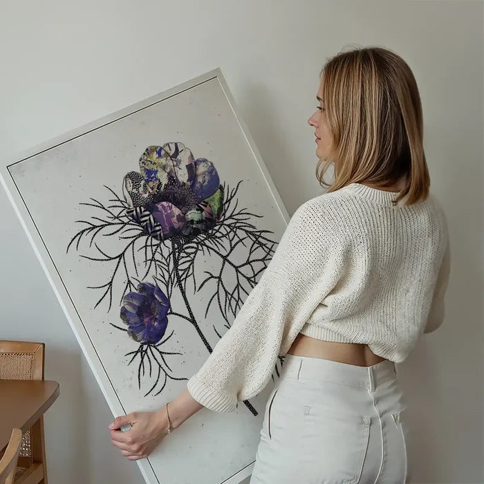 Woman holding a framed Botanical 6 White Rose Print with textured purple and green flowers on a white background.