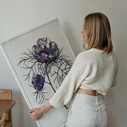Woman holding a framed Botanical 6 White Rose Print with textured purple and green flowers on a white background.