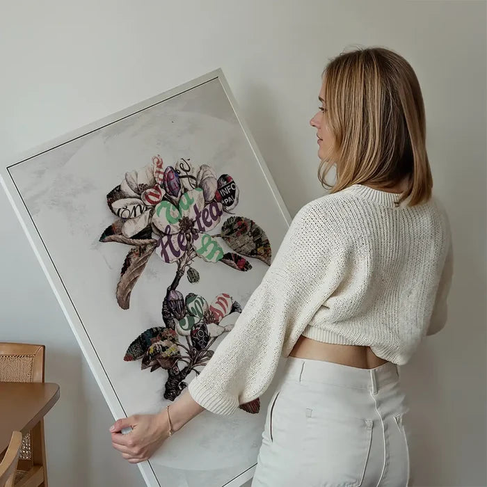 Woman holding a framed Botanical 7 Floral Typography Print with vintage text woven into colorful petals.