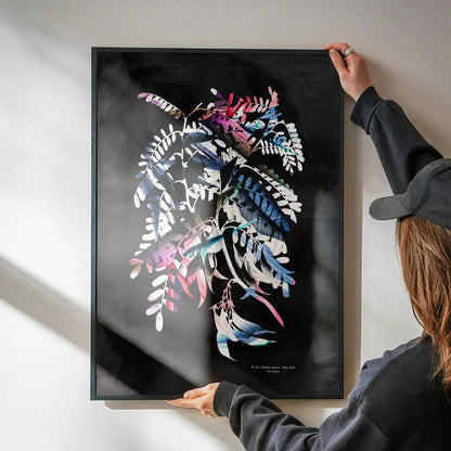 Person hanging a framed Botanical 8 Floral Print with vibrant, bold paint strokes on a black background.
