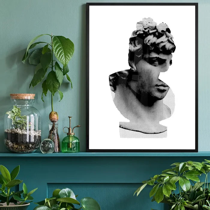 Black and white graphic print of a classic Roman bust in a black frame, on a green shelf with plants.