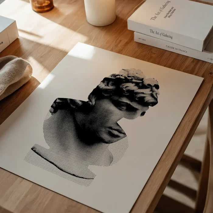 Black and white graphic print of a classic Roman bust on thick archival art paper, displayed on a wooden table.