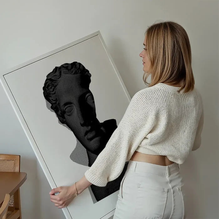 Woman holding a large black and white graphic print of a classic Roman bust on archival art paper.