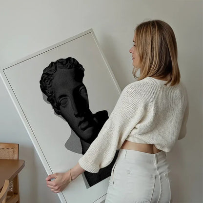 Woman holding a large black and white graphic print of a classic Roman bust on archival art paper.