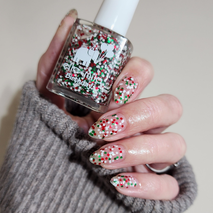 Confetti Cheer holiday confetti glitter nail polish manicure on a light skin tone, holding the bottle