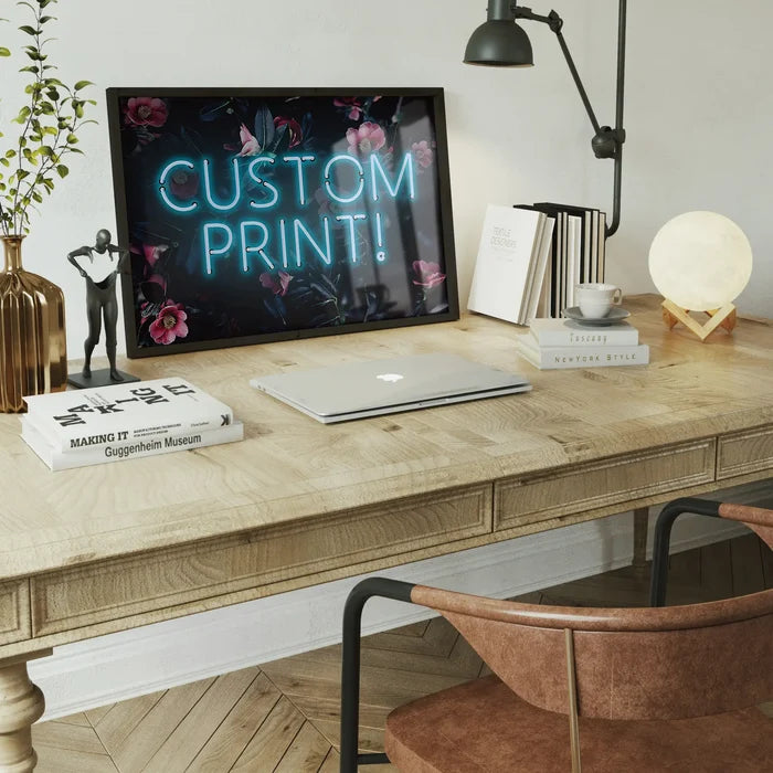 Custom blue neon sign print with floral background in a black frame, displayed on a wooden desk.