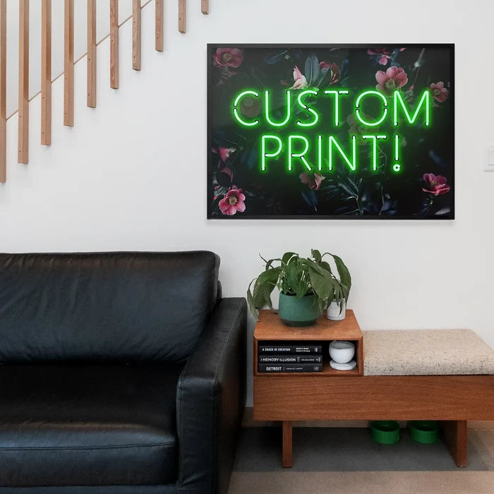 Custom green neon sign floral background print hanging above a black leather sofa.