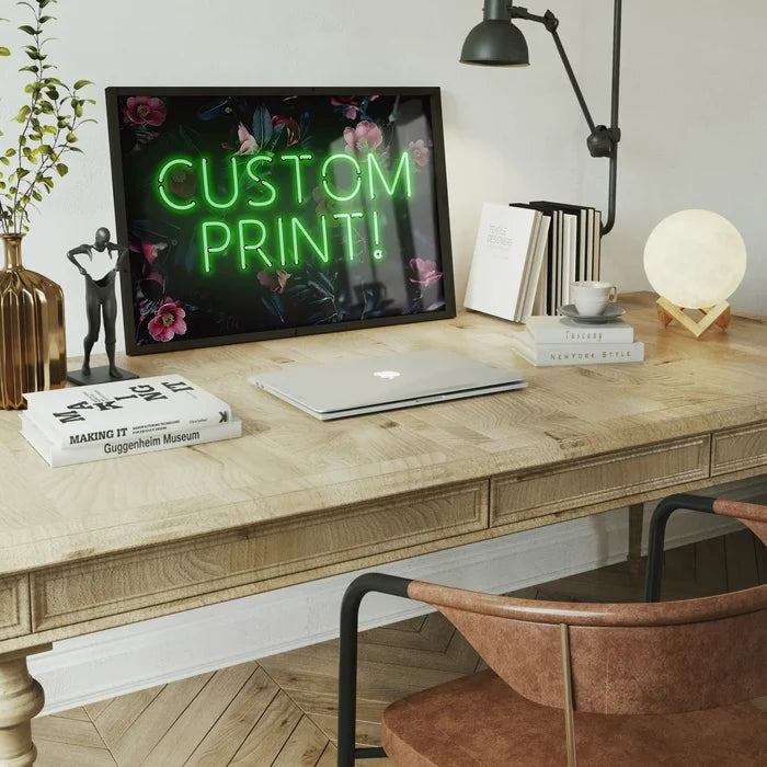 Custom green neon sign floral background print on a desk with a laptop, books, and lamp.