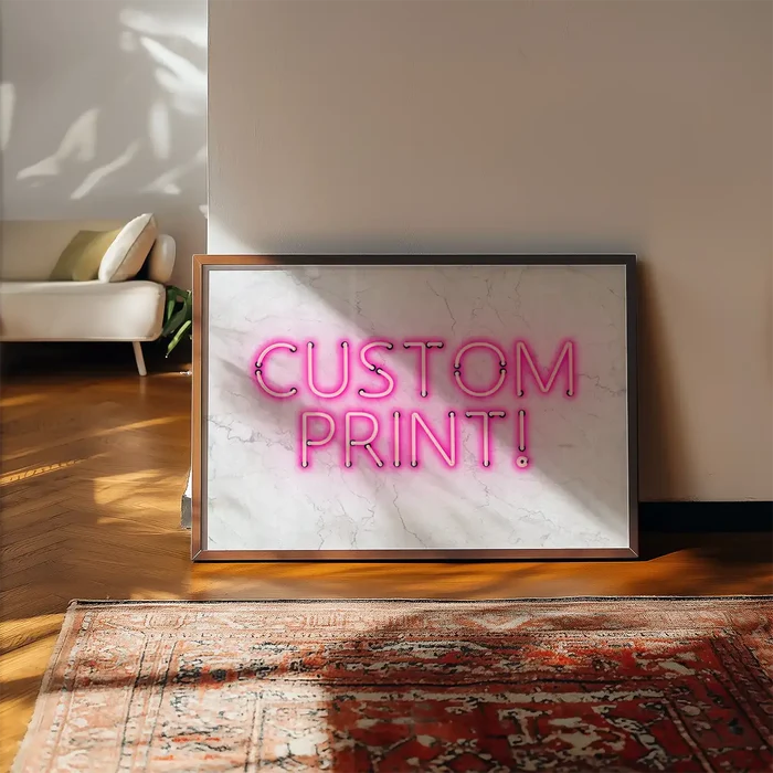 Custom "CUSTOM PRINT!" pink neon-style art print on white marble background, framed, leaning on a wall.