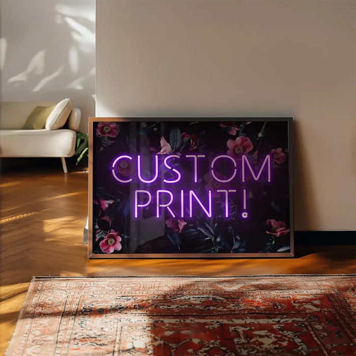 Custom purple neon sign with "CUSTOM PRINT!" text on a dark floral background, framed, leaning on a wall.