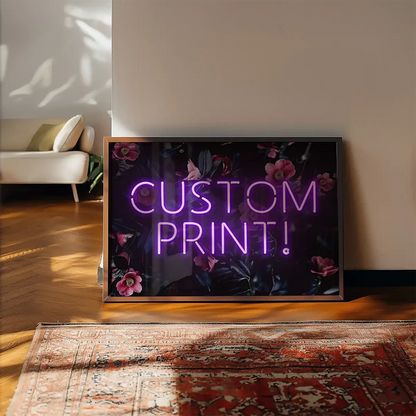 Custom purple neon sign with "CUSTOM PRINT!" text on a dark floral background, framed, leaning on a wall.