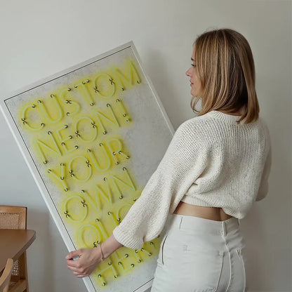 Woman holding a framed custom yellow neon print with "CUSTOM NEON! YOUR OWN QUOTE" text.
