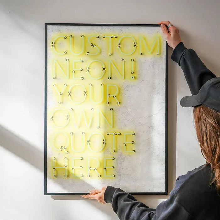 Person holding a framed custom yellow neon print with "CUSTOM NEON! YOUR OWN QUOTE HERE" text.
