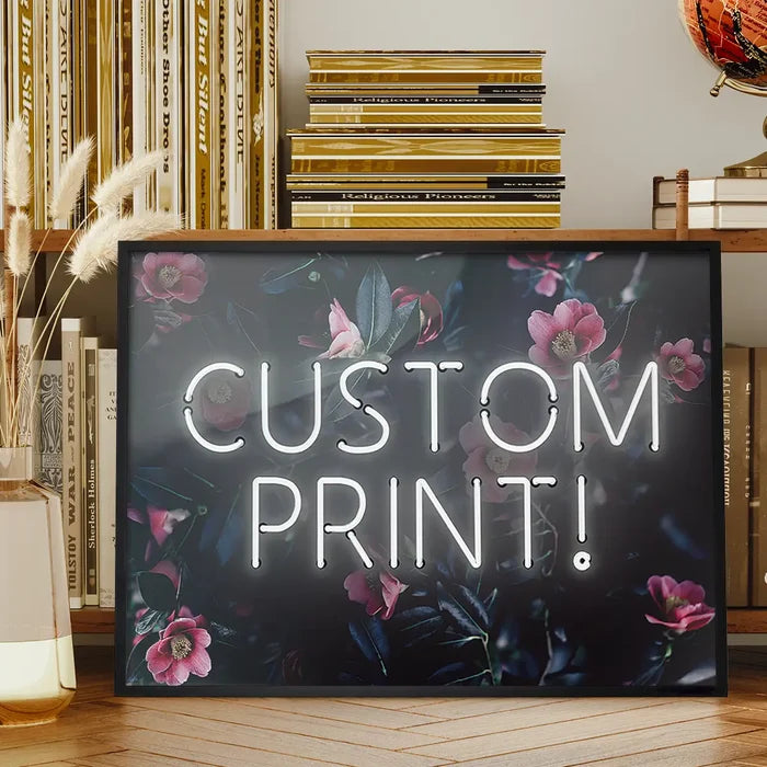 Custom white neon sign with "CUSTOM PRINT!" text over a dark floral background with pink flowers.