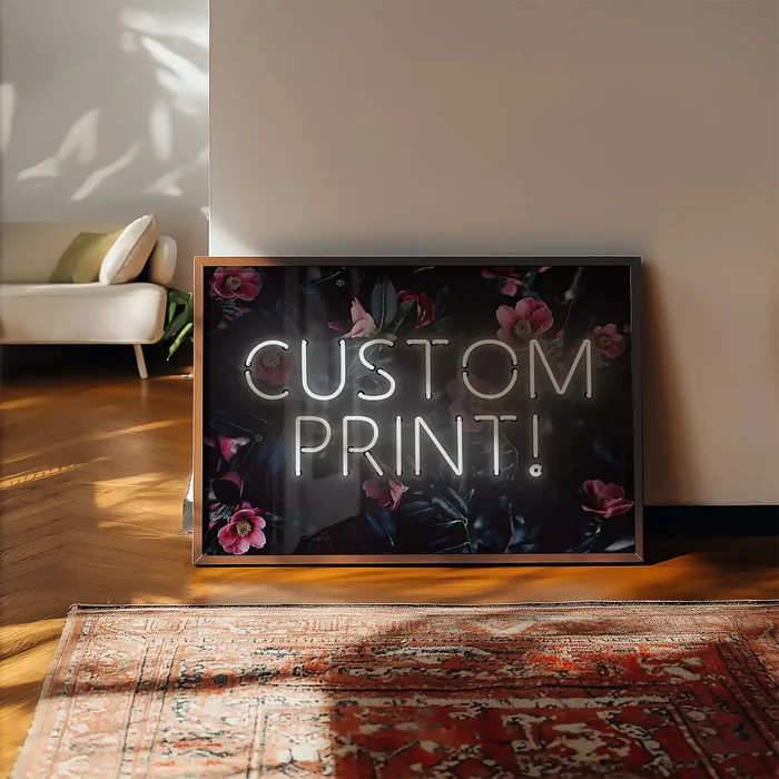 Custom white neon sign with "CUSTOM PRINT!" text on a dark floral background, leaning on a wall.