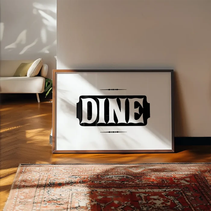 Framed "DINE" typographic print on white archival paper with ornate details, leaning on a wall above a patterned rug.