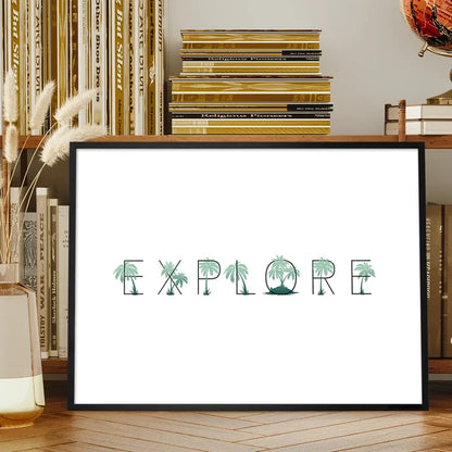 Black-framed "EXPLORE" print with green palm tree typography on white archival art paper, displayed on a wooden shelf.