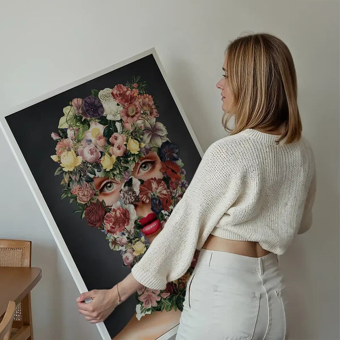 Woman holding a "Flowerclava Black Floral Print" art print with a striking graphic of a face made of colorful flowers.