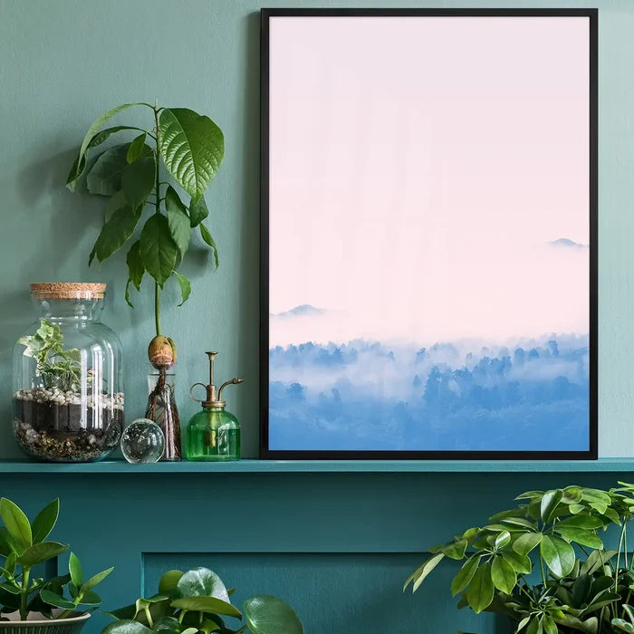 Forest Pink Blend Print: Graphic art print of misty blue mountains under a pink sky, framed on a teal shelf.