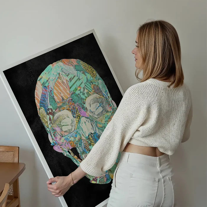 Woman holding a large framed geometric pastel pattern skull print on black art paper.