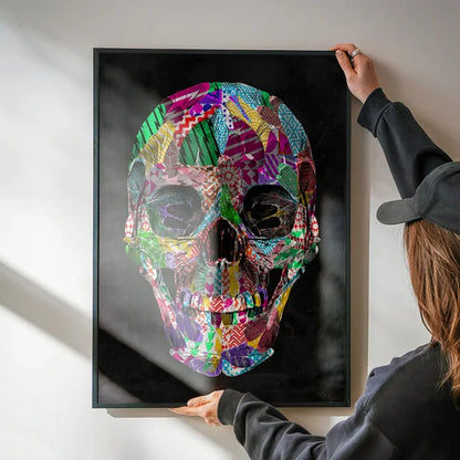 Framed geometric pattern skull print with bright, colorful shapes on black background, held by hands.