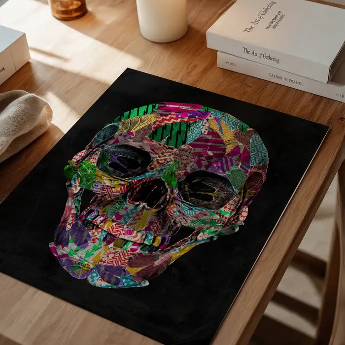 Colorful geometric pattern skull art print on black background, displayed on a wooden table.