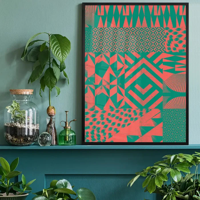 Abstract geometric art print with pink and green segments in a black frame, on a teal shelf.