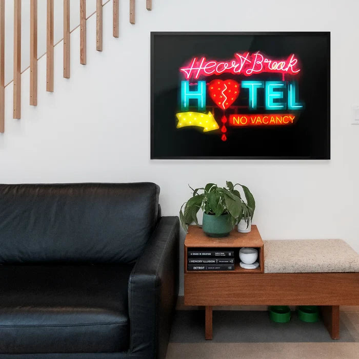 Framed Heartbreak Hotel neon sign art print with glowing red and blue text on a black background, displayed on a white wall.