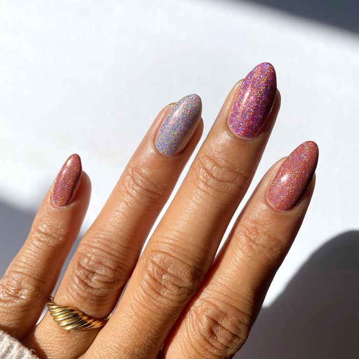 Holo Ever After holographic pink and lilac mix-and-match manicure with a gold ring in sunlight